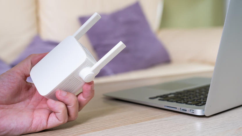 Selective focus at range extender. Internet router on working table with blurred man connect the cable at the background. Fast and high speed internet connection to cover home network usage.