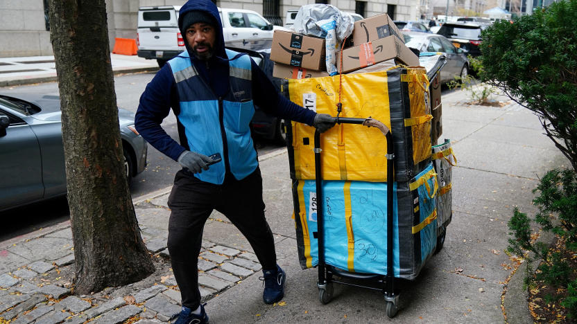 FILE PHOTO: An Amazon delivery person pulls a cart full of packages in the Manhattan borough of New York City, New York, U.S., December 10, 2021.  REUTERS/Carlo Allegri/File Photo