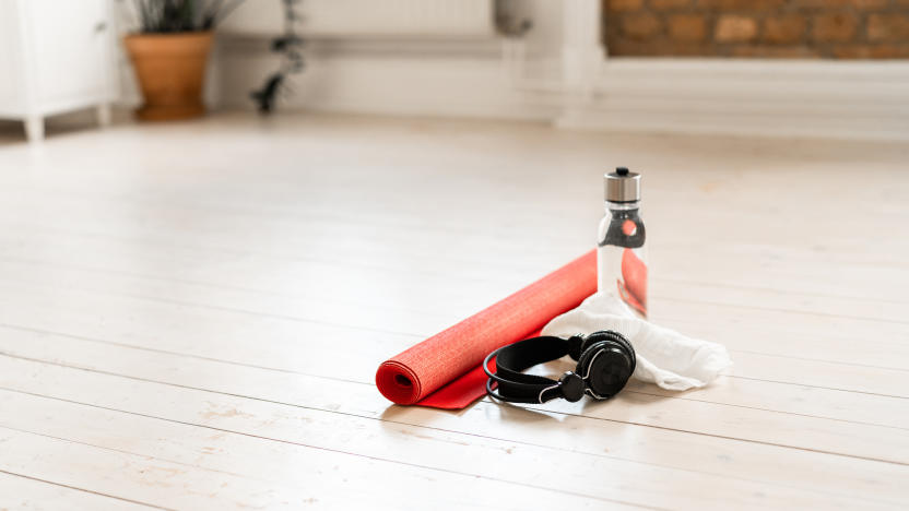 A red yoga mat on white hardwood floor in a domestic living room at home. Ready to be used in some home exercises.