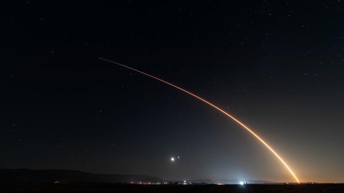 An image of an arcing trail from a rocket launch. Evening sky.