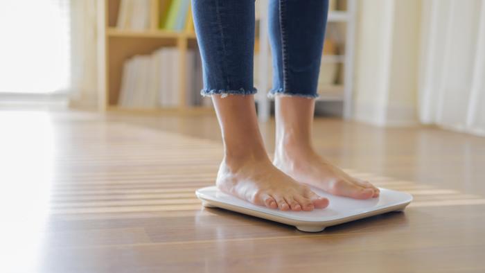 woman weighing on scale to measure her weight