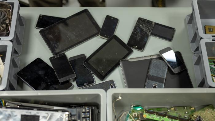 Overhead view of old smart phones and digital tablets on desk in recycling centre.